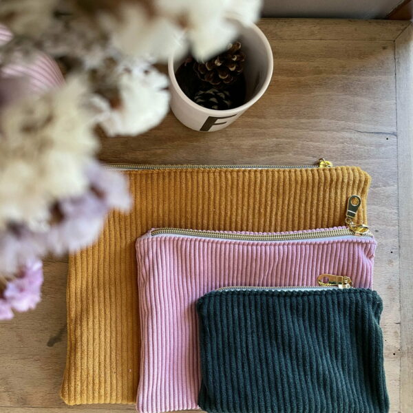 trois pochettes zippées en velours côtelé bleu marine, rose et moutarde